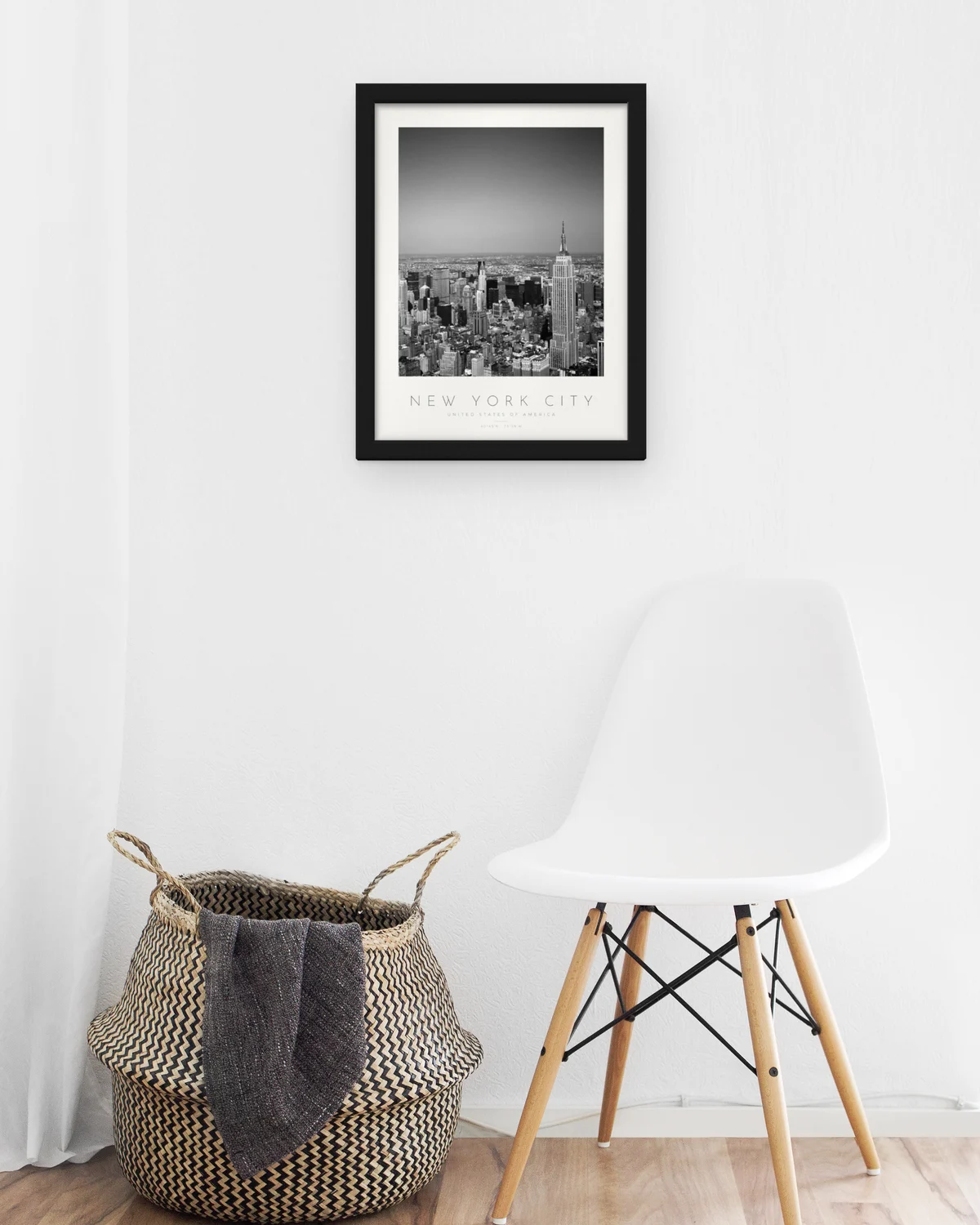 Poster Nova Iorque – Empire State com moldura preta mate numa entrada, junto a uma cadeira de verga